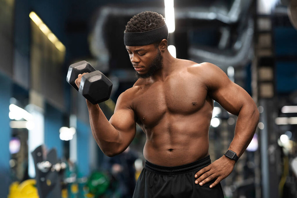 Jóképű fekete sportoló edzés karok súlyzók tornaterem - Fotó, kép