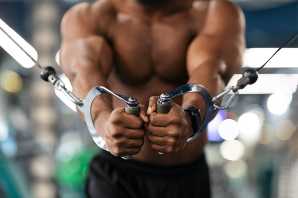 Unrecognizable black athlete training triceps on crossover exerciser in gym - Fotoğraf, Görsel