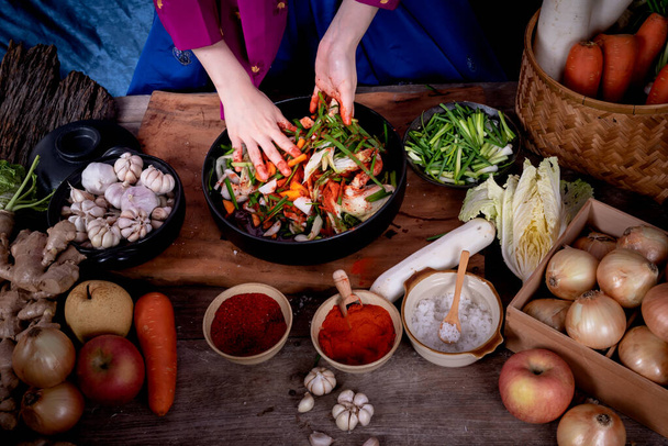 Κοντινές εικόνες από το Χέρι της Κορεάτισσας, που φτιάχνει Kimchi το οποίο είναι μια ζυμωμένη τροφή διατήρησης του κορεατικού λαού που αποτελείται από πολλά φρέσκα λαχανικά και φρούτα - Φωτογραφία, εικόνα