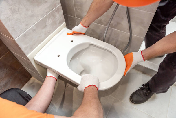 Workers are installing a wall-hung toilet on the wall. - Photo, Image