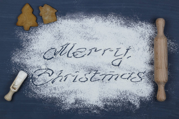 Wesołych Świąt tekst napisany z mąki na desce do krojenia i przedmiotów kuchennych. Karta noworoczna. - Zdjęcie, obraz
