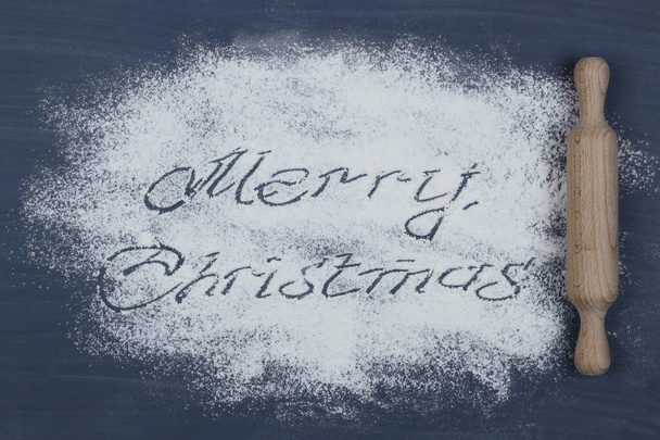 Feliz texto de Natal feito de farinha em uma tábua de corte. Cartão de Ano Novo. - Foto, Imagem