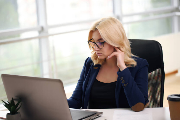 smiling blonde businesswoman with glasses using laptop in the office. - Foto, Imagem