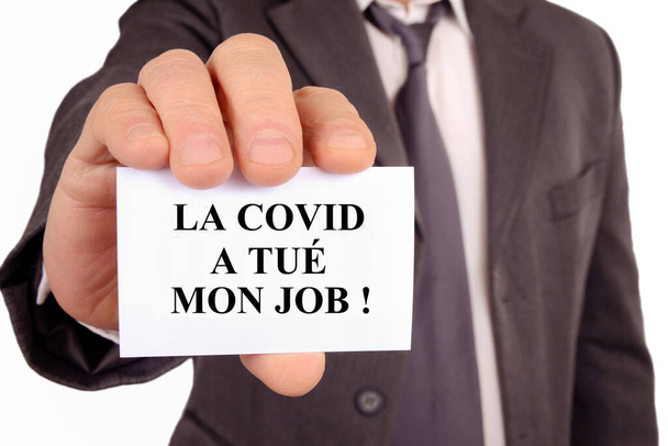 Man holding a card on which is written in French the covid killed my job - Photo, Image