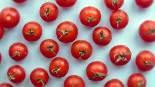 Obracające się pomidory wiśniowe na niebieskim tle. Kontekst filmu żywnościowego. Koncepcja minimalna płaska lay. - Materiał filmowy, wideo