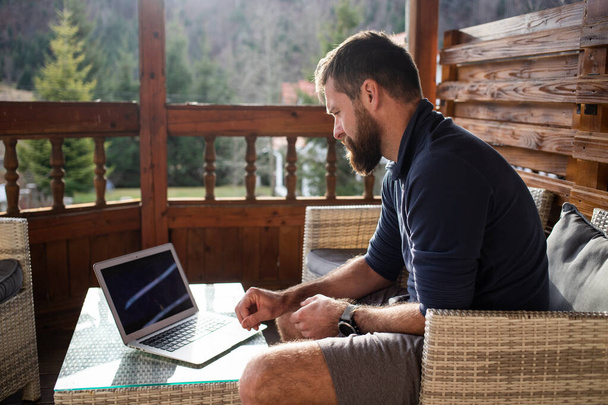 man working on laptop in wooden cottage - Fotó, kép