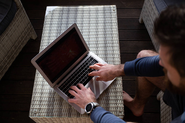 man werkt op laptop in houten huisje - Foto, afbeelding