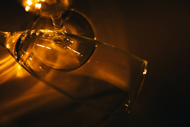 Dois copos de vinho são iluminados com luz laranja sobre um fundo escuro. Silhueta e geometria da composição. Espaço para texto - Foto, Imagem
