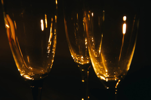 A group of several champagne glasses is beautifully lit against a dark background. A festive composition. Space for text - Фото, зображення