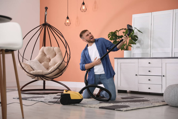 Young man having fun while vacuuming at home - Fotoğraf, Görsel