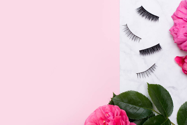 falsche Wimpern auf rosa Hintergrund mit Blumen, Kopierraum - Foto, Bild