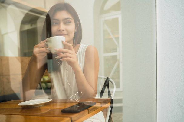 Young woman drinking a cup of coffee at coffee shop. - Foto, imagen