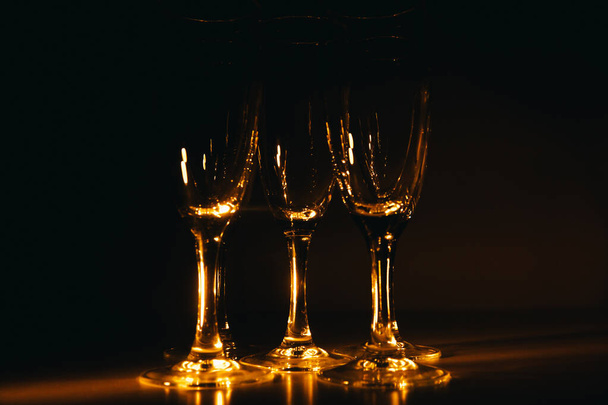 A group of several champagne glasses is beautifully lit against a dark background. A festive composition. Space for text - Fotografie, Obrázek