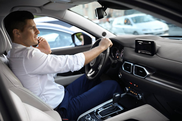 Handsome man talking on phone while driving his modern car - Fotografie, Obrázek