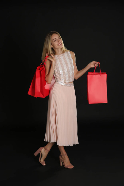 Happy young woman with shopping bags on dark background. Black Friday Sale - Foto, imagen