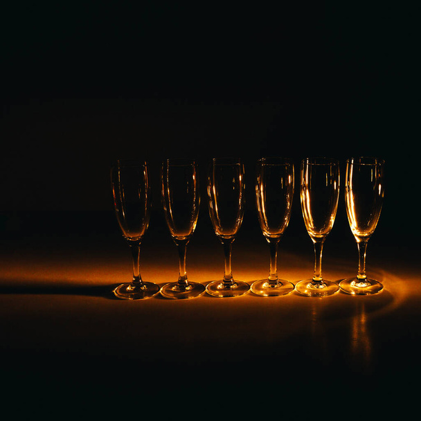 A group of several champagne glasses is beautifully lit against a dark background. A festive composition. Space for text - Foto, Bild