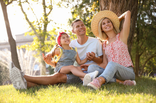 Happy parents with their child having fun on green grass. Spending time in nature - Фото, зображення