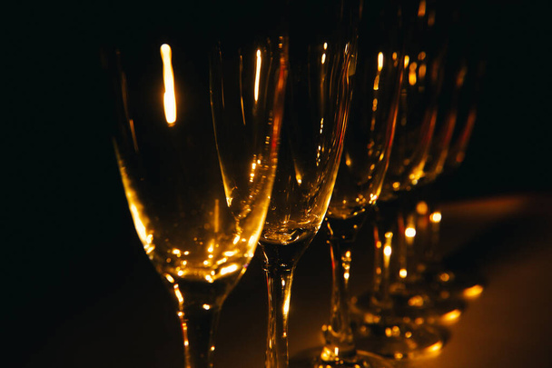 A group of several champagne glasses is beautifully lit against a dark background. A festive composition. Space for text - Foto, imagen