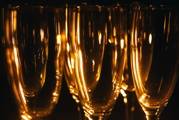 A group of several champagne glasses is beautifully lit against a dark background. A festive composition. Space for text - Fotoğraf, Görsel