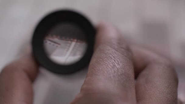 POV Blick durch Lupe auf 35mm Fotonegative. Abgeriegelt, Makro aus nächster Nähe - Filmmaterial, Video