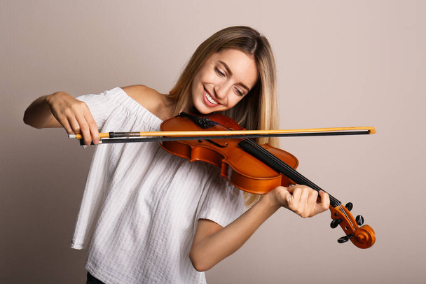Beautiful woman playing violin on beige background - Zdjęcie, obraz