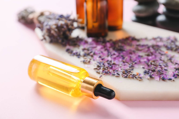 Composition with essential oil bottles and lavender twigs on color background - Photo, Image