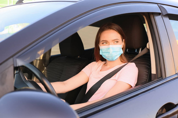 Όμορφη γυναίκα φορώντας ιατρική μάσκα στο σύγχρονο αυτοκίνητο - Φωτογραφία, εικόνα