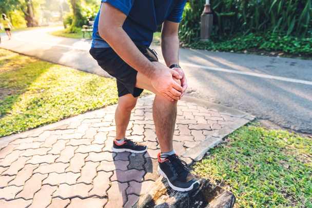 Mężczyzna, który obecnie ma kontuzję kolana Podczas ćwiczeń biegając po parku, z powodu choroby zwyrodnieniowej stawów, do sportu i opieki zdrowotnej koncepcji. - Zdjęcie, obraz