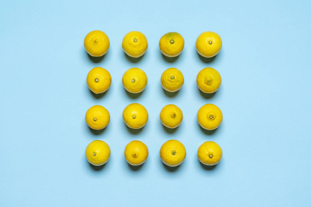 Above view with many lemons aligned symmetrically in a square on a blue background. Fresh lemons top view. - 写真・画像
