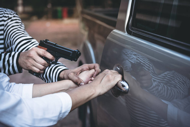 Los forajidos están cometiendo crímenes usando un arma para robar a las mujeres que están abriendo las puertas de los autos, para robar propiedad, para Peligro de los bandidos concepto. - Foto, imagen