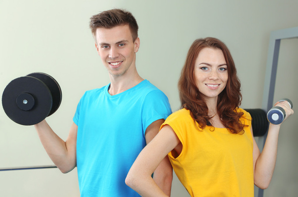 Young beautiful peoples engaged with dumbbells in gym - Foto, imagen