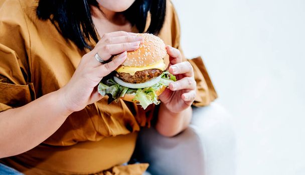 Obese women are happy With eating hamburgers, which consist of meat, fresh vegetables, breads and cheese with white background, to food and healthy concept. - Foto, immagini