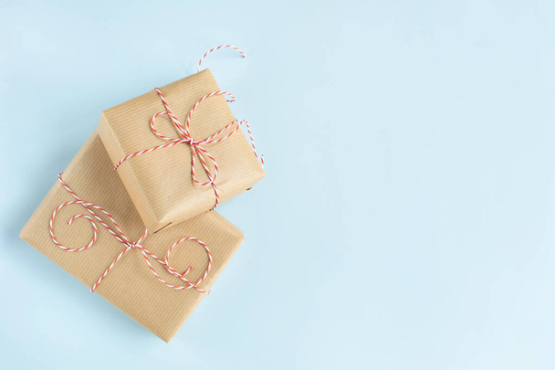 Dos regalos envueltos en papel con una cinta roja están sobre un fondo azul. Espacio libre para texto. - Foto, imagen