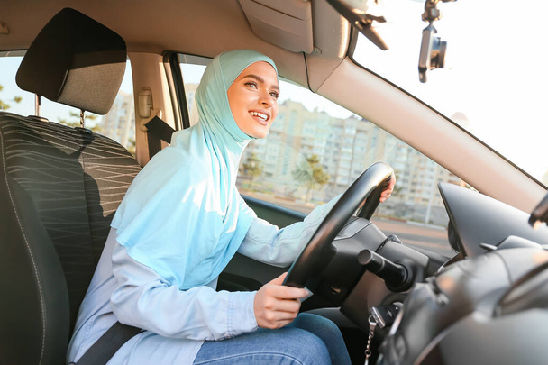 Νεαρή μουσουλμάνα γυναίκα στο σύγχρονο αυτοκίνητο - Φωτογραφία, εικόνα