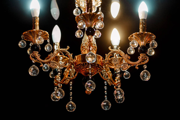 Contemporary glass chandelier isolated over black background. Chandelier for interior of the living room. Gold decoration. - Photo, Image