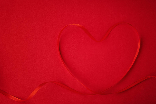 Sevgililer Günü geçmişi. Kırmızı arka planda festival kurdelesinden yapılmış bir kalp. Sevgililer Günü konsepti. Üst manzara, düz uzanma - Fotoğraf, Görsel