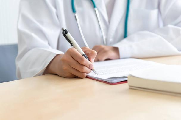 Doutor está escrevendo um relatório sobre os sintomas do paciente na mesa, para o conceito de cuidados de saúde. - Foto, Imagem