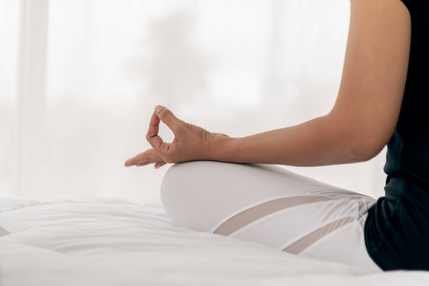 Женщины практикуют йогу в основном положении на белой кровати, которая является разогревом и медитацией упражнения, концепция здравоохранения и отдыха - Фото, изображение