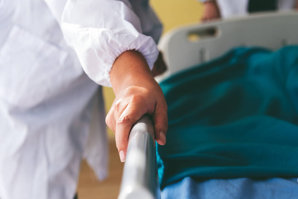 La mano del dottore, che sta spingendo il letto del paziente per curare i sintomi, in ospedale al concetto di salute. - Foto, immagini