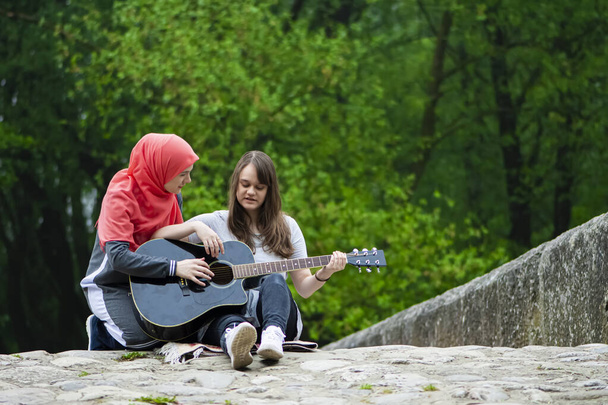 Duas meninas muçulmanas jovens que têm aula de guitarra - Foto, Imagem