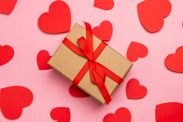 Gift box present with red bow for valentine's day, declaration of love. Composition with red hearts for Valentine's Day on a pale pink background. Flat lay. Love and relationships concept. - Foto, Imagem