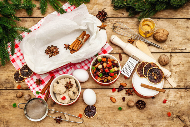 Vánoční pečení pozadí2021. Tradiční saský Stollen s ovocem a ořechy. Složení potravin na nový rok vaření. Slavnostní výzdoba, dřevěné desky, výhled shora - Fotografie, Obrázek