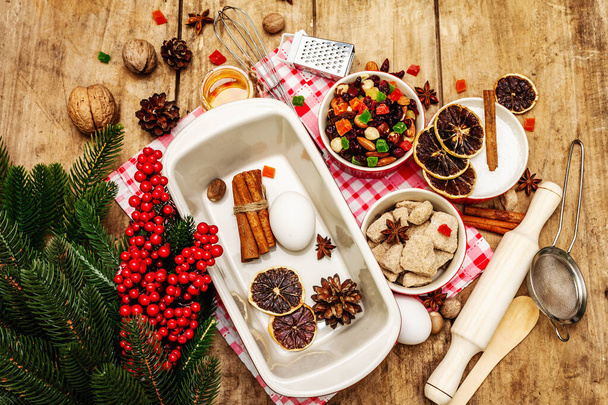 Christmas baking background 2021. Traditional Saxon Stollen with fruits and nuts. Food Ingredients for New Year cooking. Festive decor, wooden boards, top view - Photo, Image