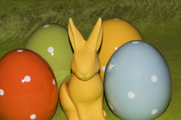 Colorful ceramic easter eggs and an Easter bunny in front of a green background - Photo, Image