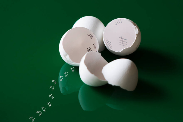 Cáscaras de huevo rotas, reflejos y rastros de un polluelo escapado frente a un fondo verde con espacio para saludos de Pascua. - Foto, imagen