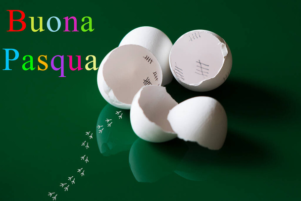 Kırık yumurta kabukları, yansımalar ve yeşil arka plan önünde kaçan bir civcivden alınan izler ile renkli Paskalya selamları. Çeviri: Buona Pasqua" - Fotoğraf, Görsel