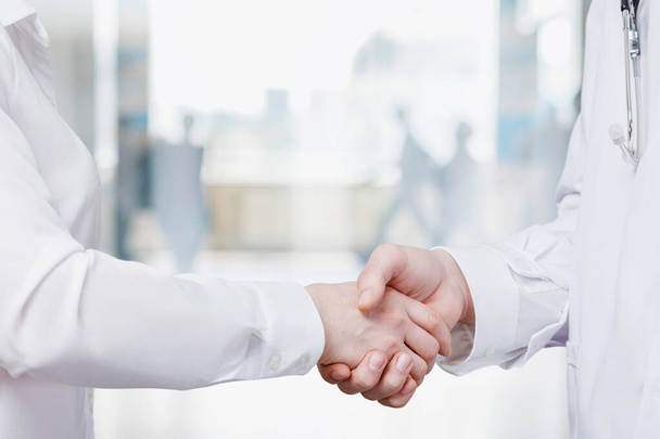 Medical cooperation concept. Doctors handshake on blurred hospital background. - Photo, Image