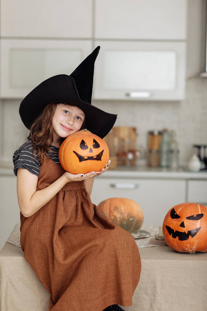 Buon Halloween. Ragazzina carina in costume da strega con zucca intagliata. Famiglia felice che si prepara per Halloween - Foto, immagini