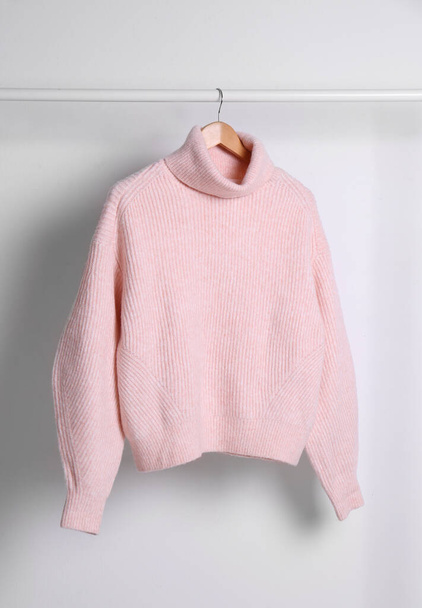 Warm sweater hanging on rack against white background - Фото, зображення