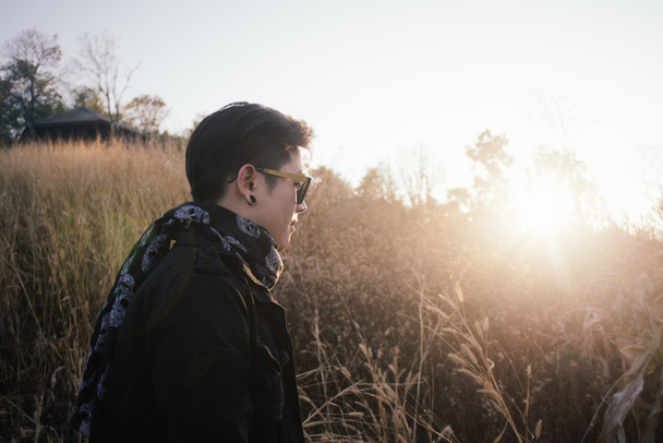молодий чоловік у полі трави зі сходом сонця
 - Фото, зображення